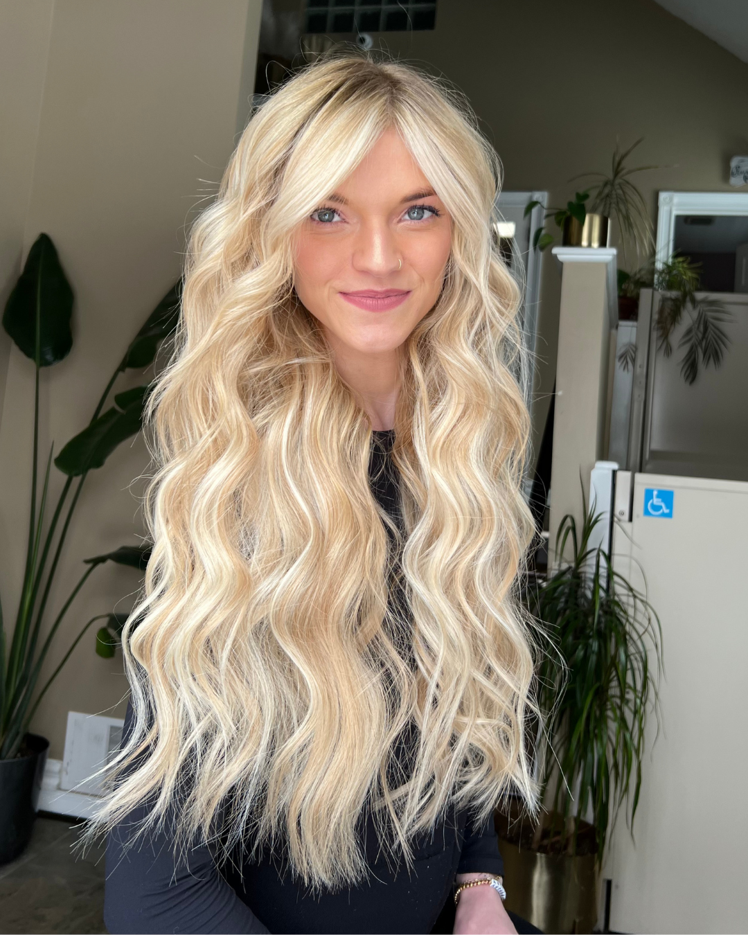 Client after applying Stitched Seam Weft™ extensions — voluminous, wavy blonde hair with seamless blend and enhanced shine