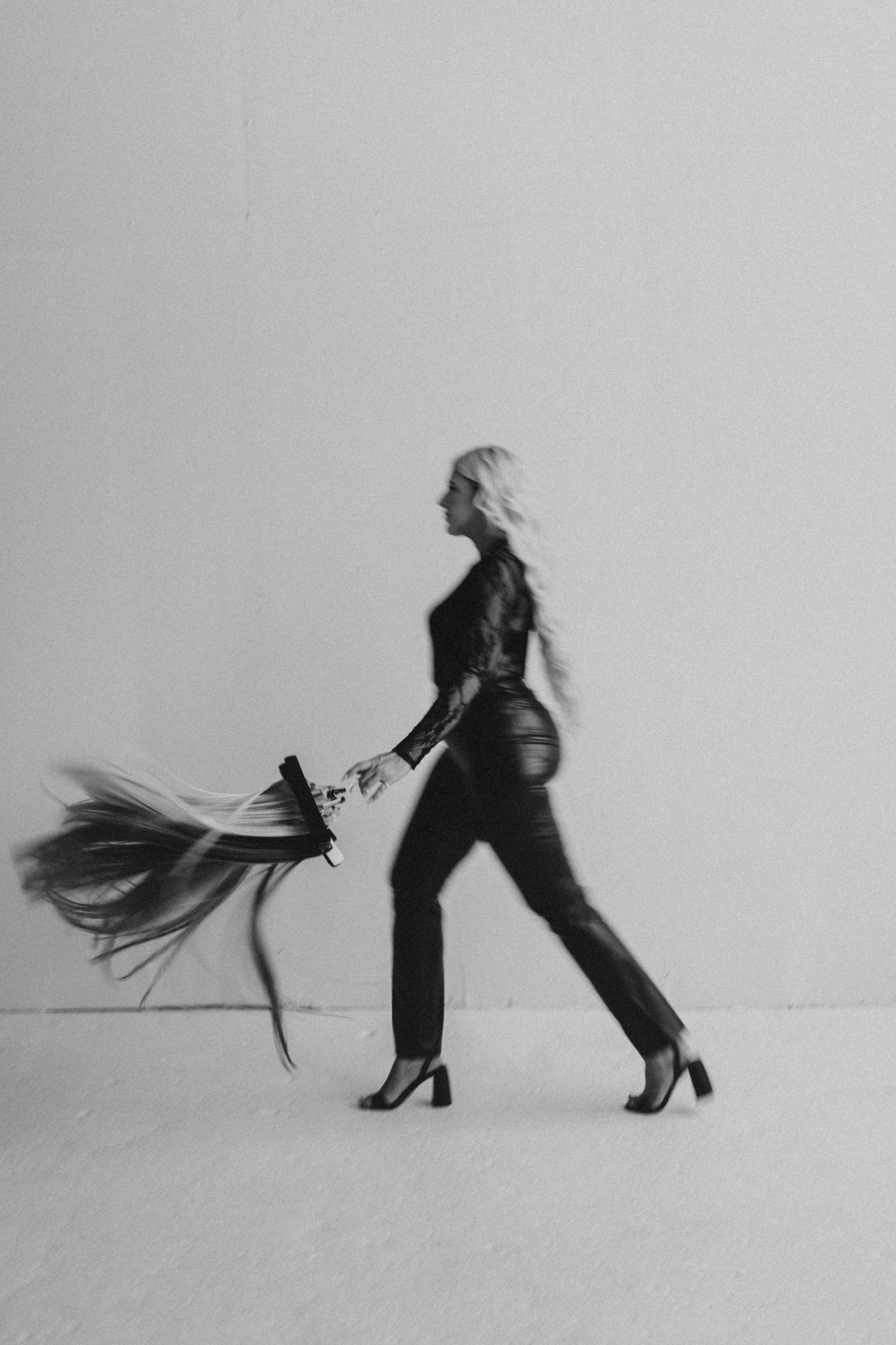 Person in a black outfit holding a long, holding Stitched Hair wefts against a plain background