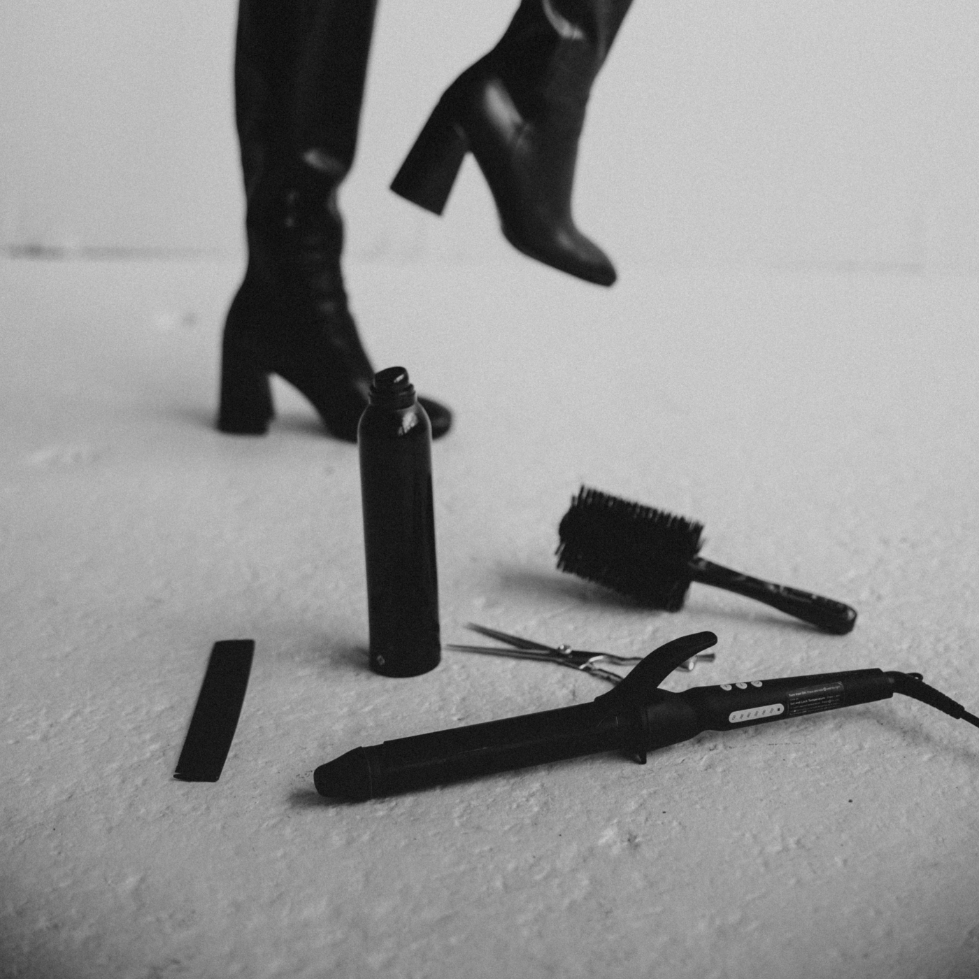 Styling tools and high-heeled boots on a white floor symbolizing fast, professional hair extension shipping and delivery.